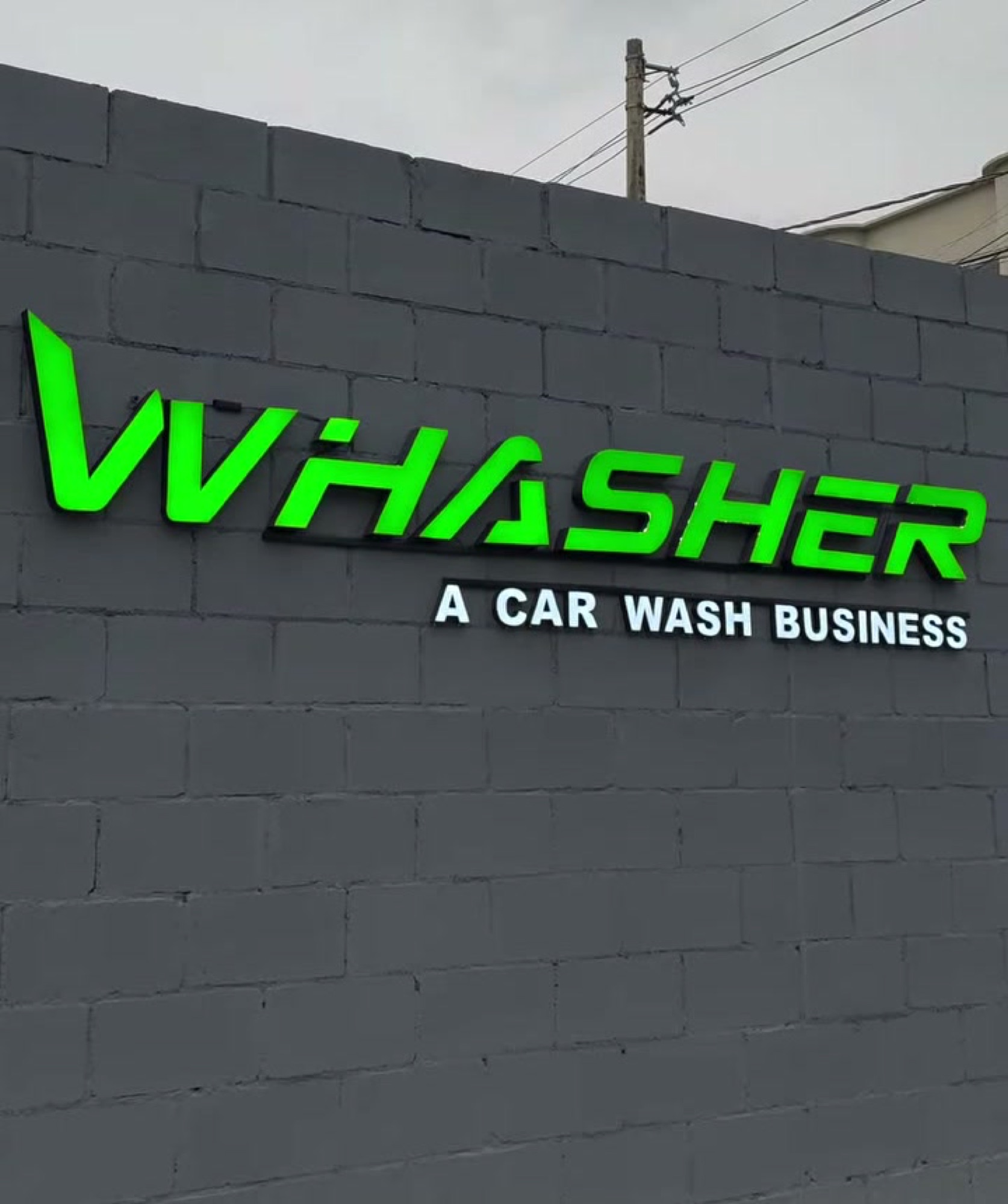 Fachada do Whasher com a logo verde iluminada no muro, na Av. Afonso Pena