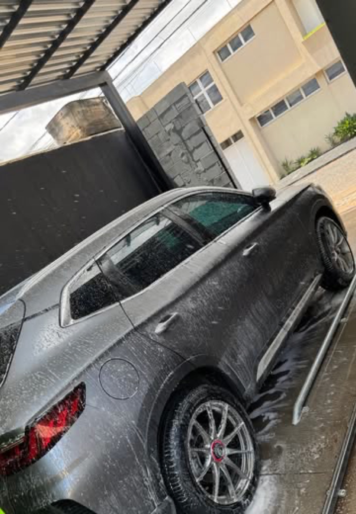 SUV cinza com espuma na pista de lavagem do Whasher